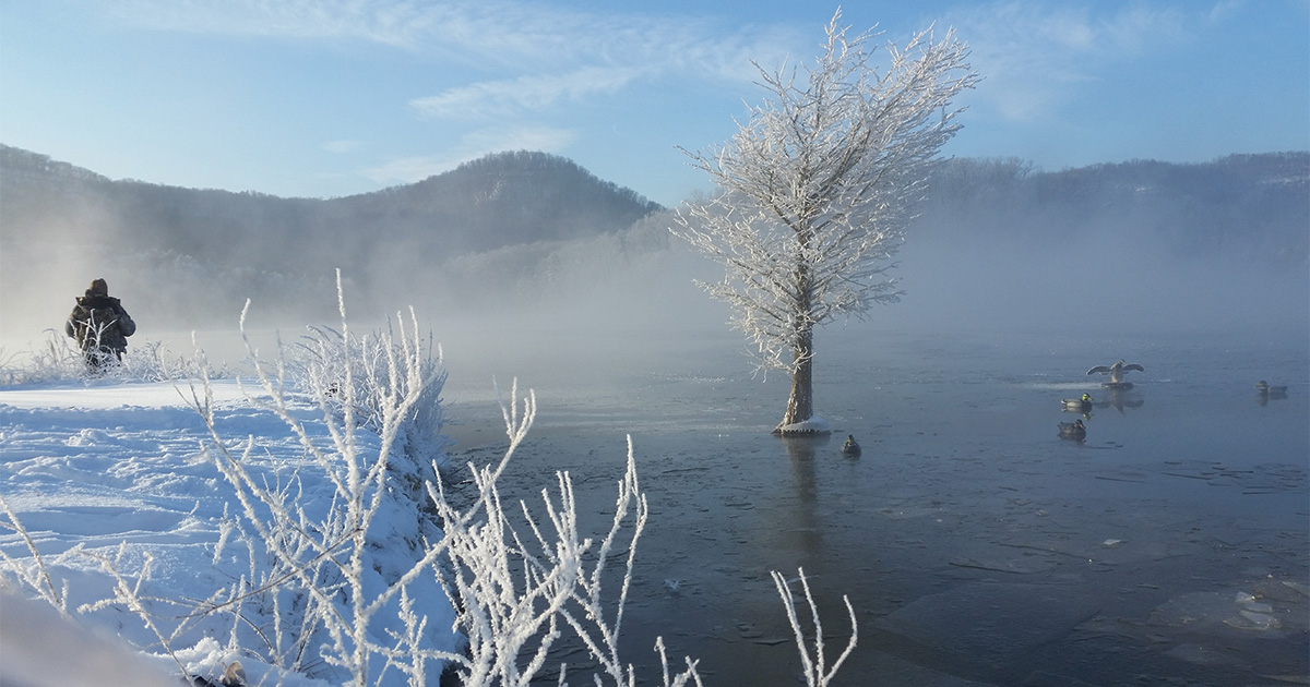 Hunter looking over frozen pond and decoys. Photo by Kevin Anderson