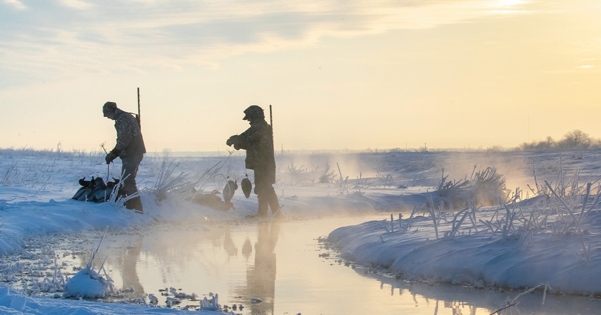 Hunters putting out decoys in a stream during winter. Photo by dougsteinkephotos.com